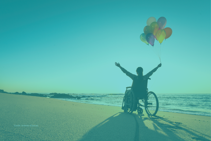 Zu sehen ist eine Person im Rollstuhl am Strand mit Luftballons.